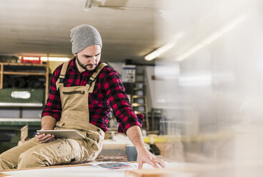 Arbeiter mit Tablet, der in der Werkstatt einen Entwurf betrachtet - UUF12666