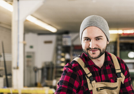 Porträt eines lächelnden Arbeiters in einer Werkstatt - UUF12667