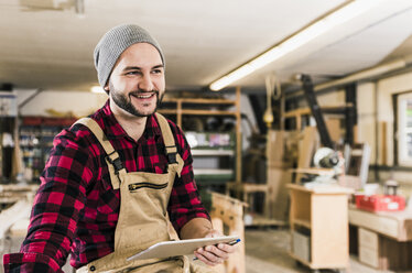 Lächelnder Arbeiter mit Tablet in der Werkstatt - UUF12668