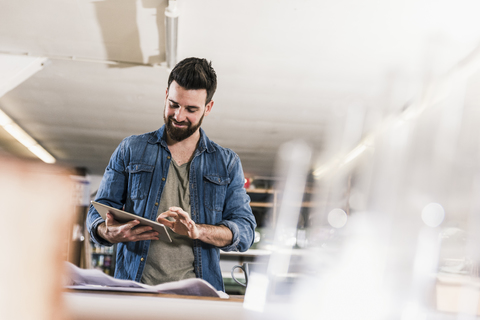 Lächelnder Mann mit Tablet und Entwurf in der Werkstatt, lizenzfreies Stockfoto