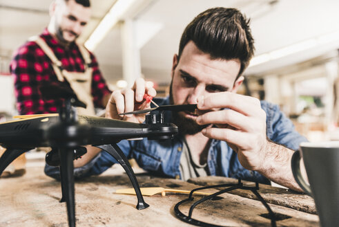 Mann arbeitet in der Werkstatt an einer Drohne - UUF12680
