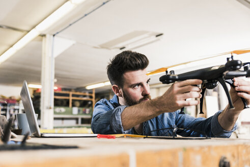 Mann arbeitet in der Werkstatt an einer Drohne - UUF12681