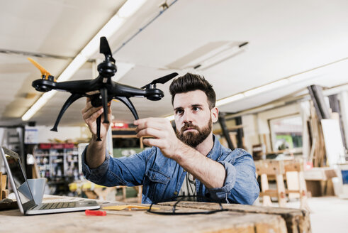 Mann arbeitet in der Werkstatt an einer Drohne - UUF12682