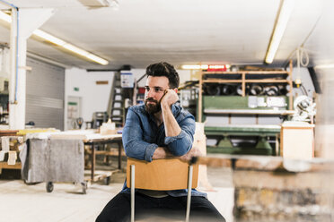 Man sitting on chair in workshop - UUF12684