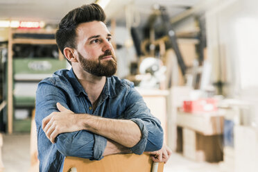 Man sitting on chair in workshop - UUF12686