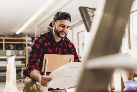 Arbeiter betrachtet den Entwurf in der Werkstatt, lizenzfreies Stockfoto