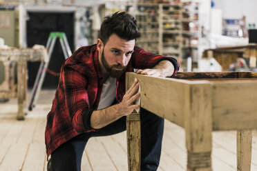 Mann behandelt Holz in der Werkstatt mit Schleifpapier - UUF12712