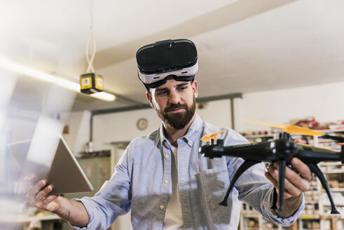 Mann mit VR-Brille hält Drohne und Tablet - UUF12723