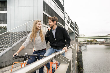 Lächelndes Paar mit Fahrrädern in der Stadt - PESF00991