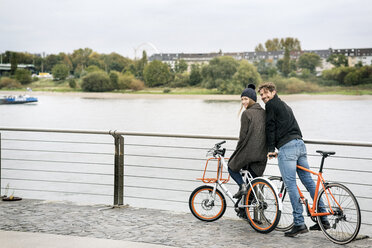 Lächelndes Paar mit Fahrrädern am Flussufer - PESF01003