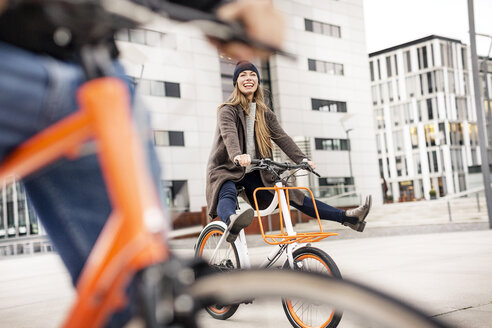 Unbekümmerte Frau mit Mann beim Fahrradfahren in der Stadt - PESF01006