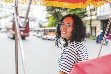 Vietnam, Hanoi, Porträt einer lächelnden jungen Frau auf einer Riksha in der Stadt - WPEF00060