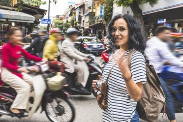 Vietnam, Hanoi, Porträt einer lächelnden jungen Frau inmitten des Verkehrs in der Stadt - WPEF00061