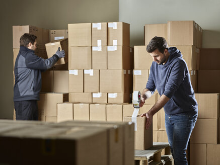 Arbeiter, die Pakete mit Paketband verschließen - CVF00108