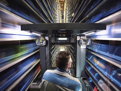 Worker operating high rack in storehouse stock photo