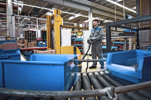 Mann bei der Arbeit in einer Fabrik mit Kisten auf einem Förderband - CVF00126