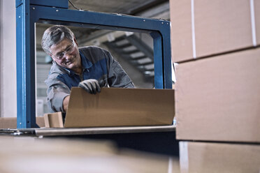 Arbeiter an einer Maschine, die Pakete verschließt - CVF00129