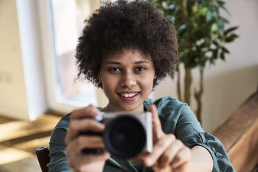 Portrait of smiling young woman holding camera - FMKF04819