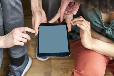 Vier Personen teilen sich ein Tablet, lizenzfreies Stockfoto