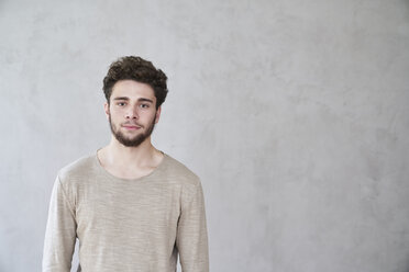 Porträt eines selbstbewussten jungen Mannes vor einer grauen Wand - FMKF04840