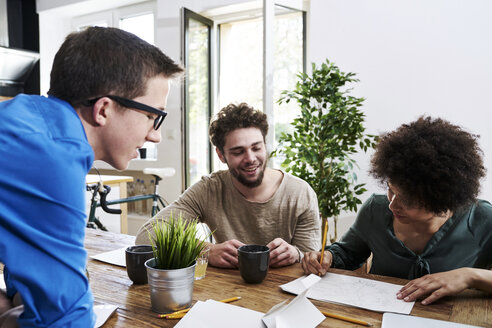 Mitarbeiter arbeiten zusammen und machen sich Notizen am Tisch im Büro - FMKF04847