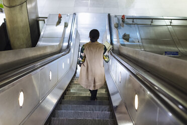 Rückenansicht einer Geschäftsfrau, die auf einer Rolltreppe einer U-Bahn-Station steht - MAUF01330