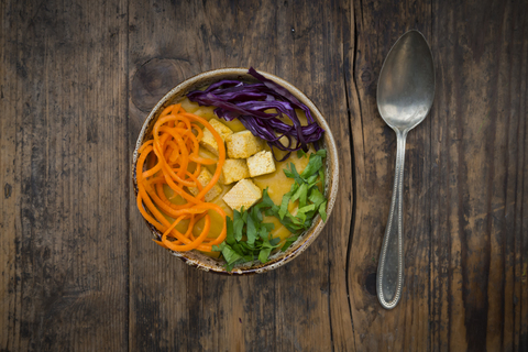 Turmeric curry dish with carrot, tofu, red cabbage and parsley in bowl stock photo