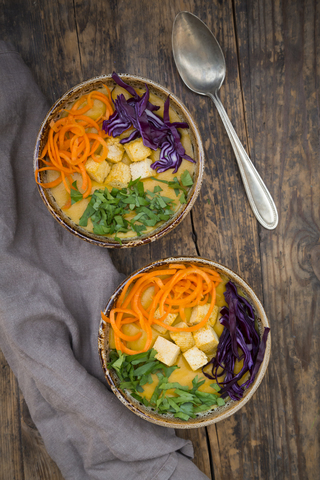 Kurkuma-Curry-Gericht mit Karotten, Tofu, Rotkohl und Petersilie in Schale, lizenzfreies Stockfoto