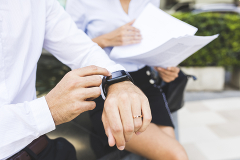 Businessman with smartwatch and businesswoman with documents in the city stock photo