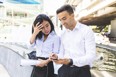 Thailand, Bangkok, Geschäftsmann und Geschäftsfrau in der Stadt mit Mobiltelefon - WPEF00074