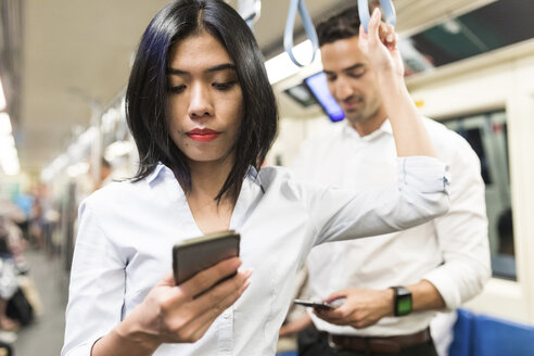 Geschäftsmann und Geschäftsfrau benutzen Handys in der U-Bahn - WPEF00084