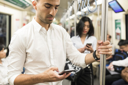 Geschäftsmann und Geschäftsfrau benutzen Handys in der U-Bahn - WPEF00085