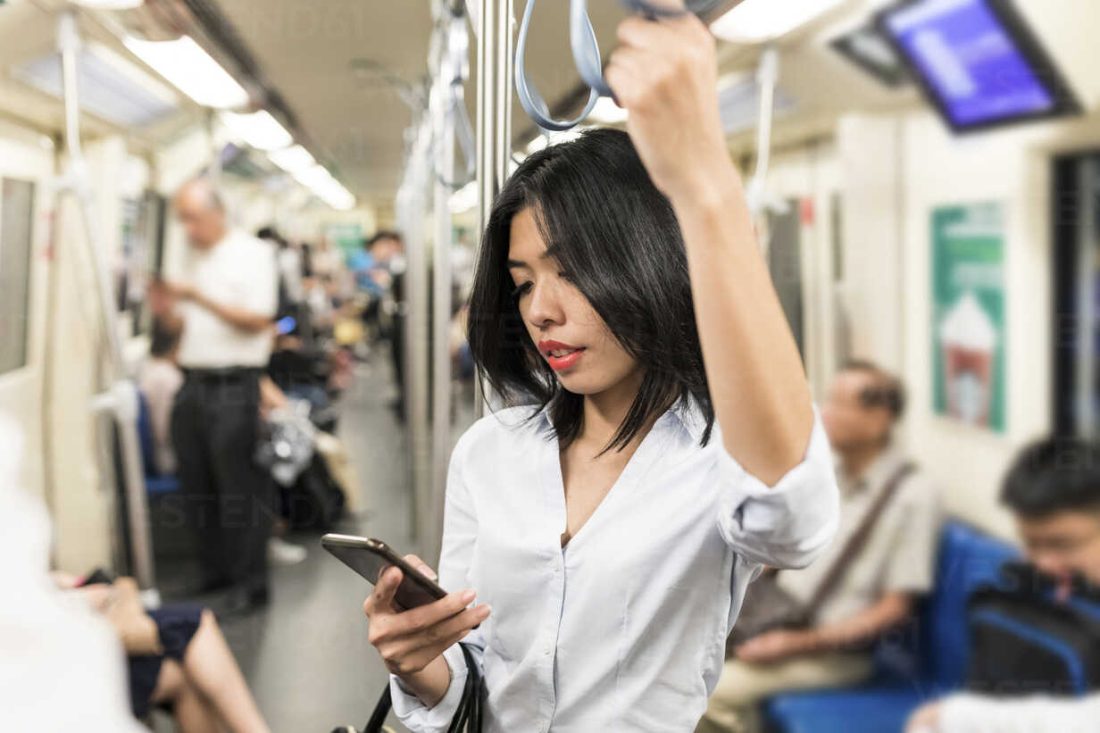 Businesswoman using cell phone in the subway stock photo