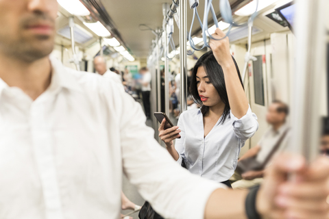 Businesswoman using cell phone in the subway stock photo