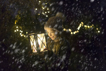 Happy girl with lighted lantern by night at snowfall - SARF03544