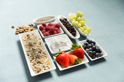 zutaten für Müsli, Chiasamen, Quark, Cranberries, Weintrauben, Heidelbeeren, Himbeeren, Erdbeeren, Mandeln, lizenzfreies Stockfoto