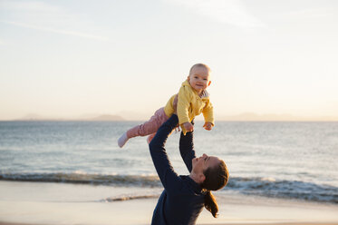 Mutter hebt kleine Tochter am Strand hoch - DIGF03240