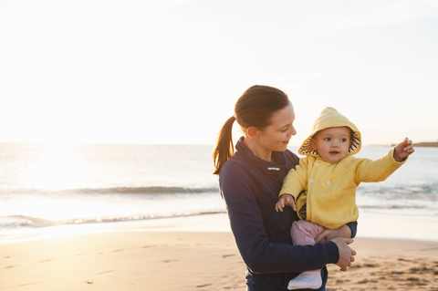 Mother holding little daughter on the beach stock photo