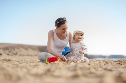 Mother playing with little daughter on the beach stock photo