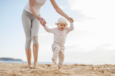 Mutter hilft ihrer kleinen Tochter beim Spaziergang am Strand - DIGF03256