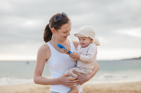 Mother holding little daughter on the beach stock photo