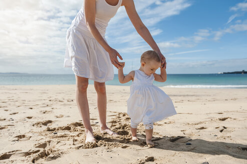 Mother helping little daughter walking on the beach - DIGF03259