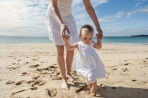 Mother helping little daughter walking on the beach - DIGF03260