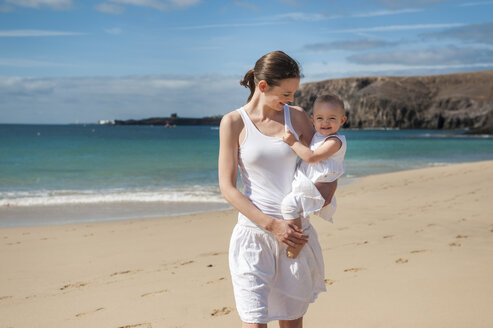 Mother holding little daughter on the beach - DIGF03261