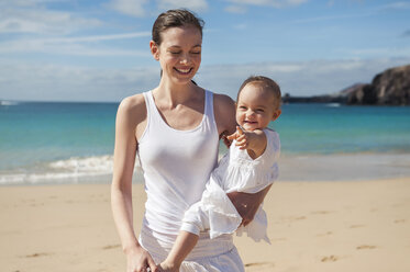 Mother holding little daughter on the beach - DIGF03262