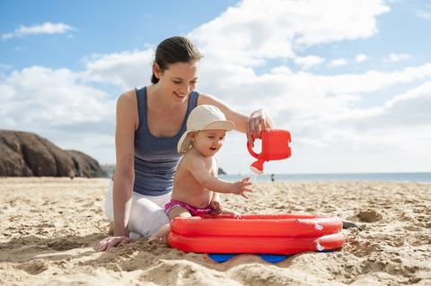 Mutter spielt mit kleiner Tochter am Strand, lizenzfreies Stockfoto