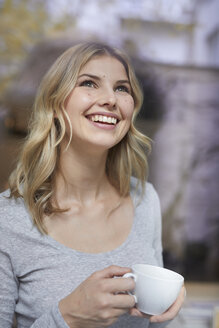 Porträt einer glücklichen Frau mit Kaffeetasse, die nach oben schaut - PNEF00520