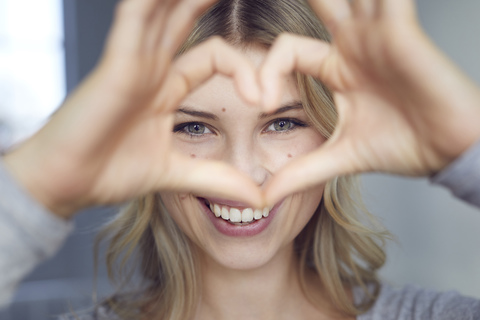 Portrait of laughing woman building heart with her fingers stock photo