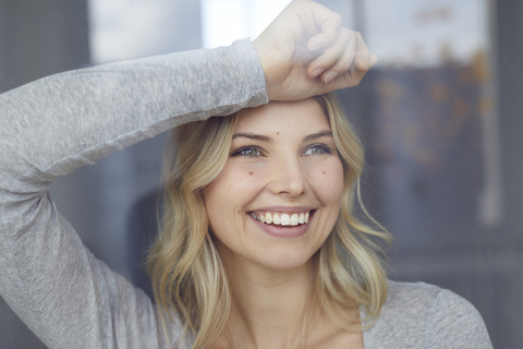 Porträt einer glücklichen Frau, die aus dem Fenster schaut, lizenzfreies Stockfoto