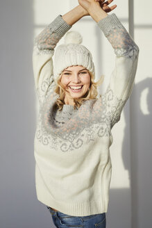 Porträt einer lachenden Frau mit Strickpullover und Bommelmütze - PNEF00531